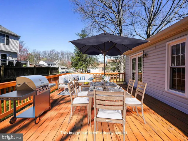 a view of a patio with couches table and chairs under an umbrella with wooden floor