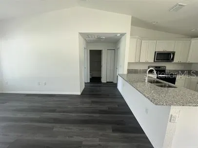 a view of a kitchen with kitchen island a sink wooden floor and a window