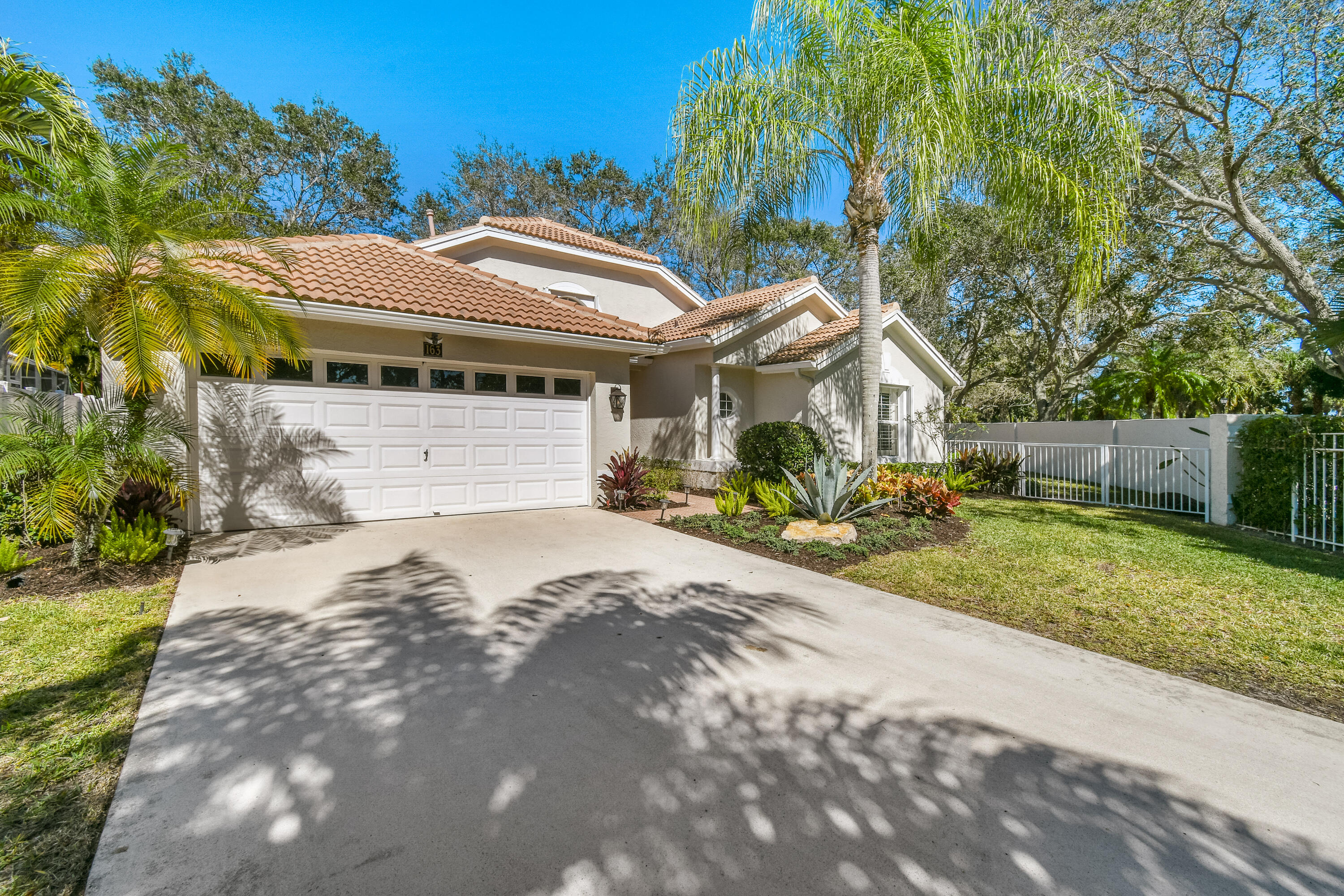 163 Spoonbill Court Jupiter, FL 33458 - Photo 3 of 67 a view of a white house with a small yard and large trees