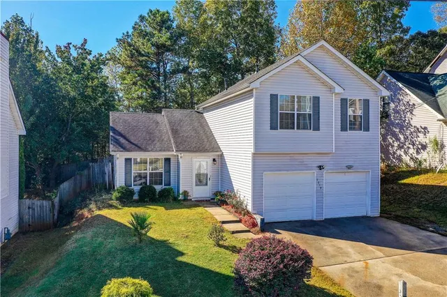 a view of a house with a big yard plants and large tree