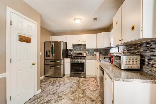 a kitchen with granite countertop a refrigerator and a stove top oven