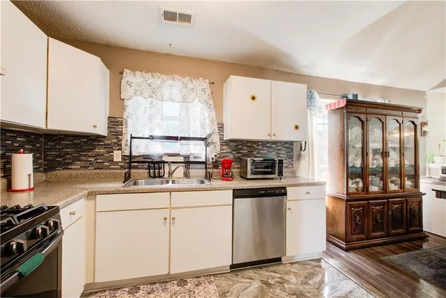 a kitchen with granite countertop a sink appliances cabinets and counter space
