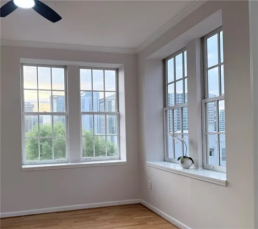 an empty room with wooden floor fan and windows