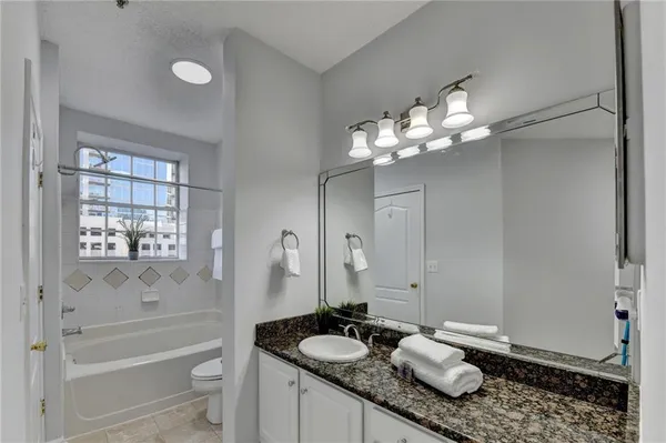 a bathroom with a granite countertop sink mirror toilet and bathtub