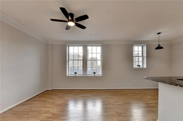 a view of an empty room with window and wooden floor