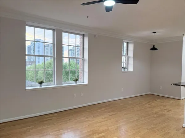 a view of an empty room with a window and chandelier fan