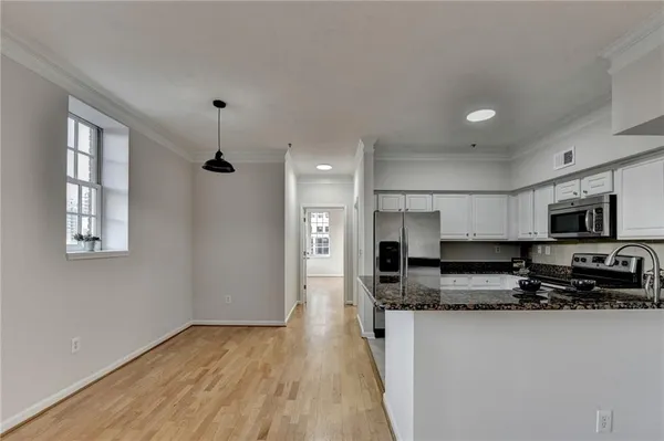 a view of kitchen with stainless steel appliances granite countertop a stove a sink a refrigerator white cabinets and wooden floor
