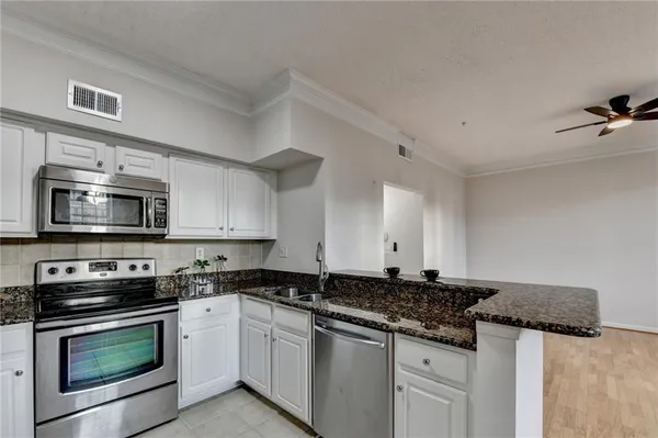 a kitchen with stainless steel appliances granite countertop a stove a microwave and a sink