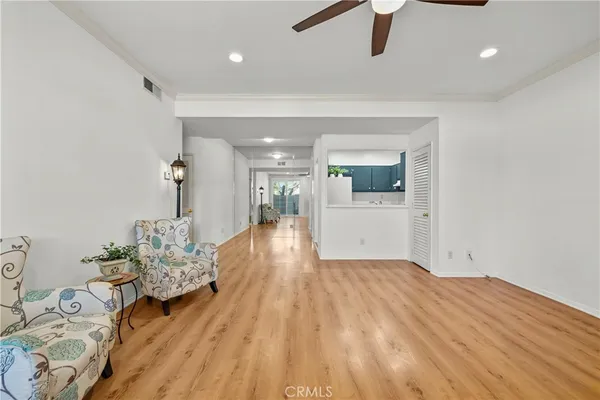 a view of a livingroom with wooden floor and a kitchen space