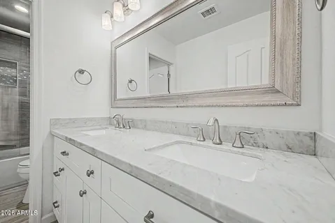 a bathroom with a granite countertop sink a toilet and bathtub