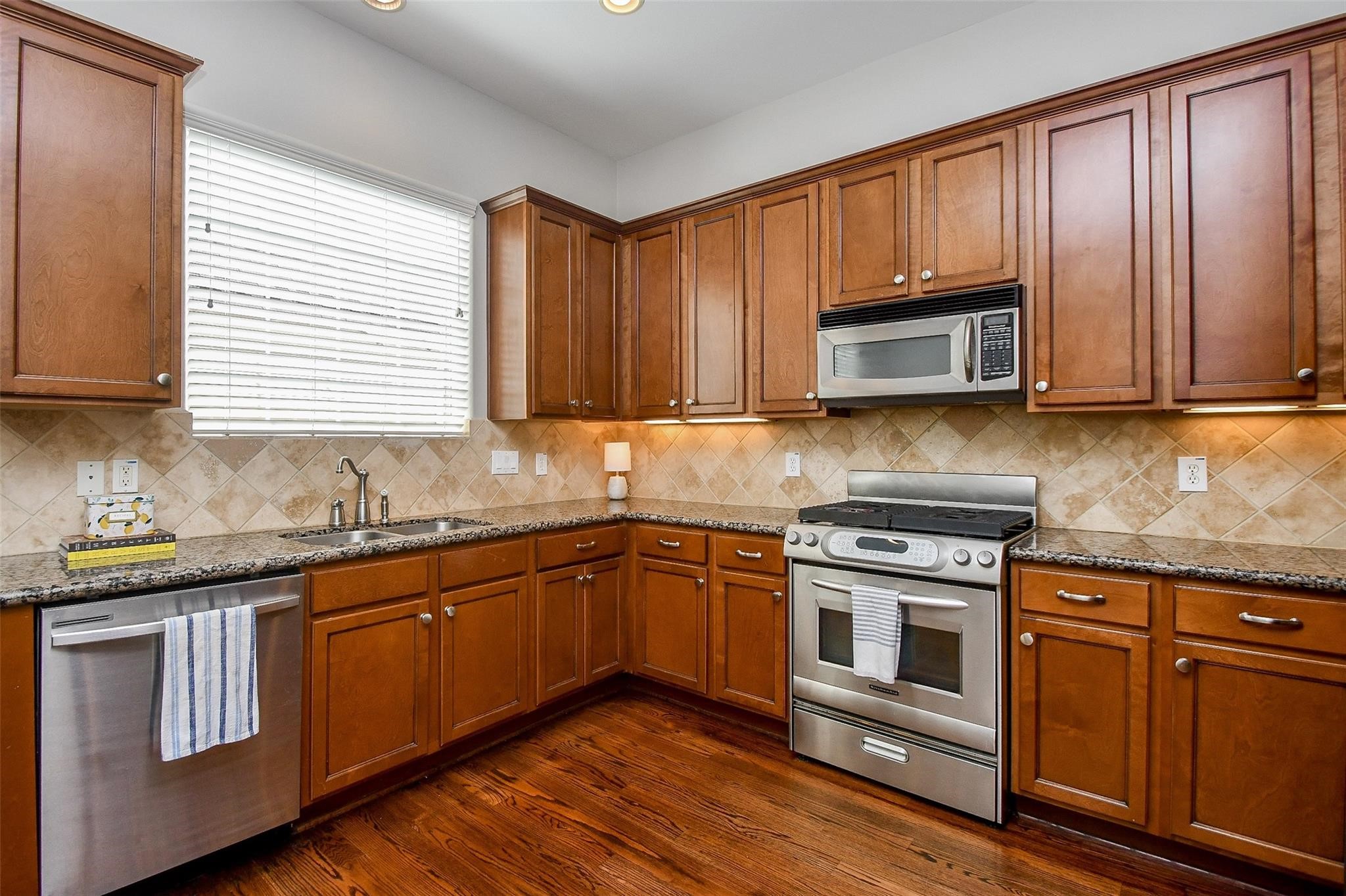2614 Maxroy Street Houston, TX 77007 - Photo 14 of 32 a kitchen with stainless steel appliances granite countertop wooden cabinets a stove a sink and dishwasher with wooden floor