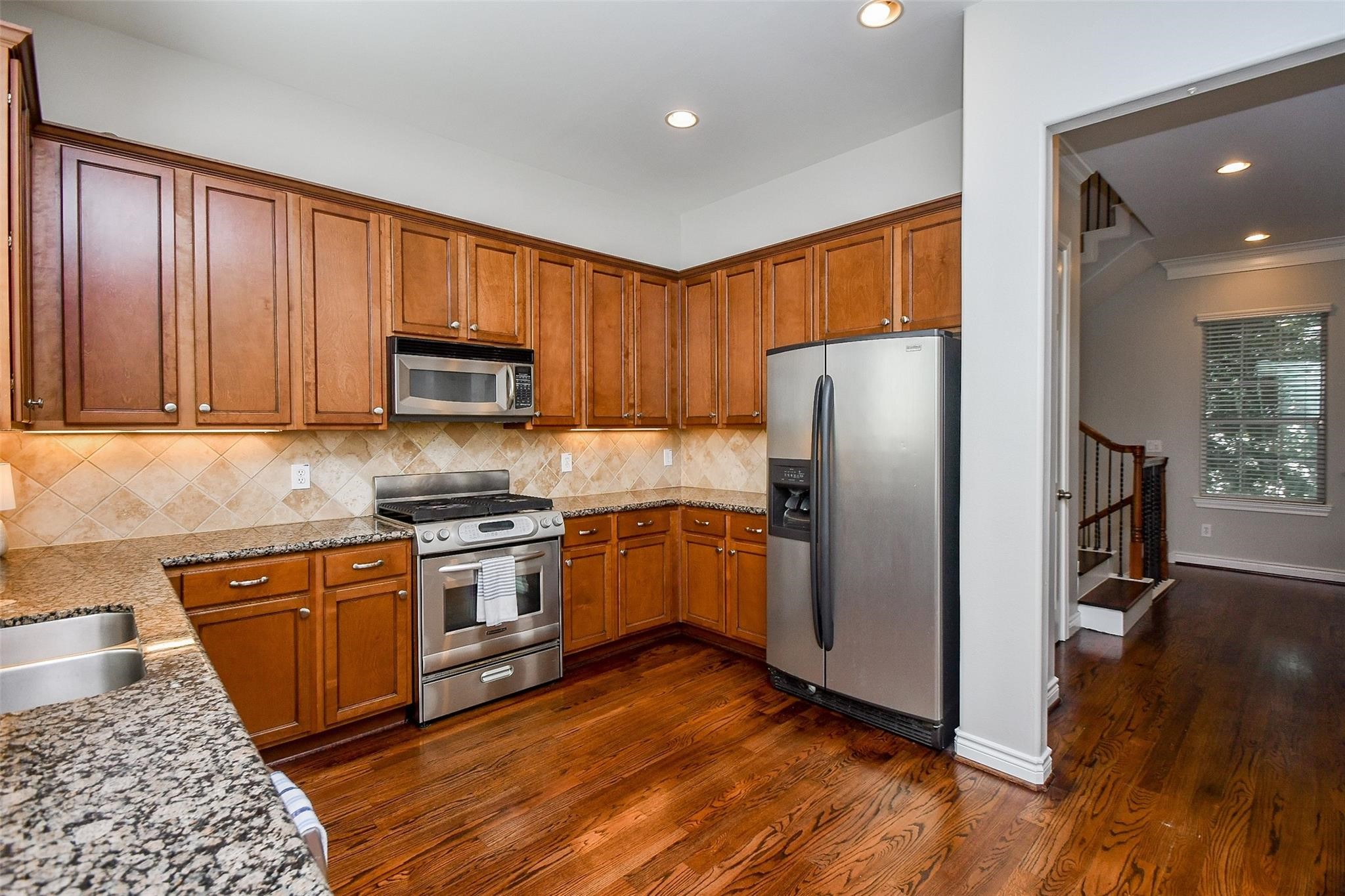 2614 Maxroy Street Houston, TX 77007 - Photo 16 of 32 a kitchen with granite countertop wooden floors stainless steel appliances and a window