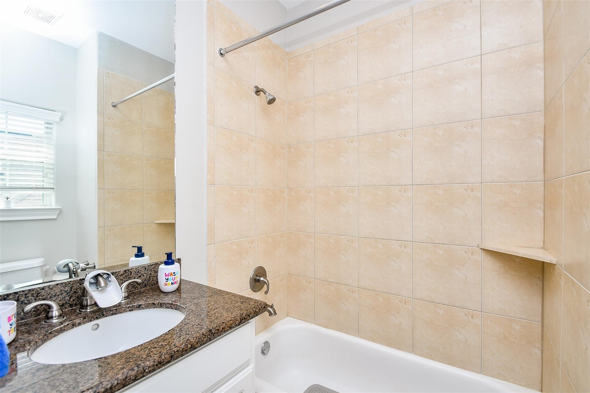 2614 Maxroy Street Houston, TX 77007 - Photo 26 of 32 a bathroom with a granite countertop sink a mirror and a bathtub