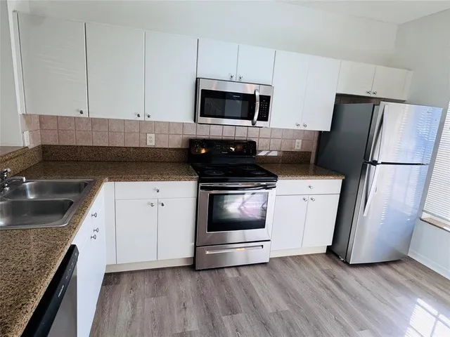 a kitchen with granite countertop white cabinets and white appliances