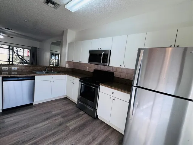 a kitchen with a sink a refrigerator a microwave a stove and cabinets