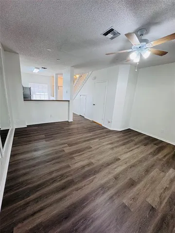 a view of an empty room with wooden floor and a ceiling fan