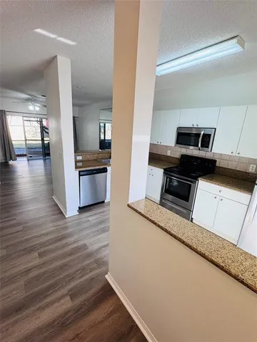 a kitchen view with wooden floor and stainless steel appliances