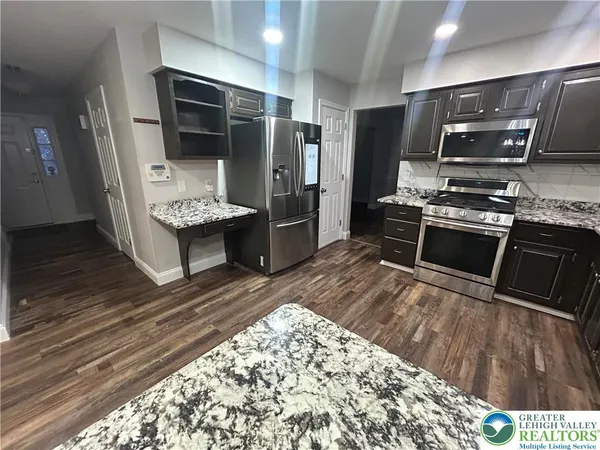 a kitchen with stainless steel appliances kitchen island granite countertop a refrigerator stove and oven