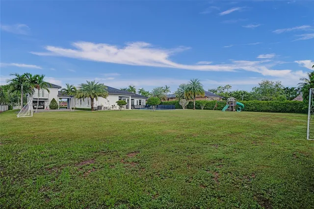 a view of a green field with house in the background