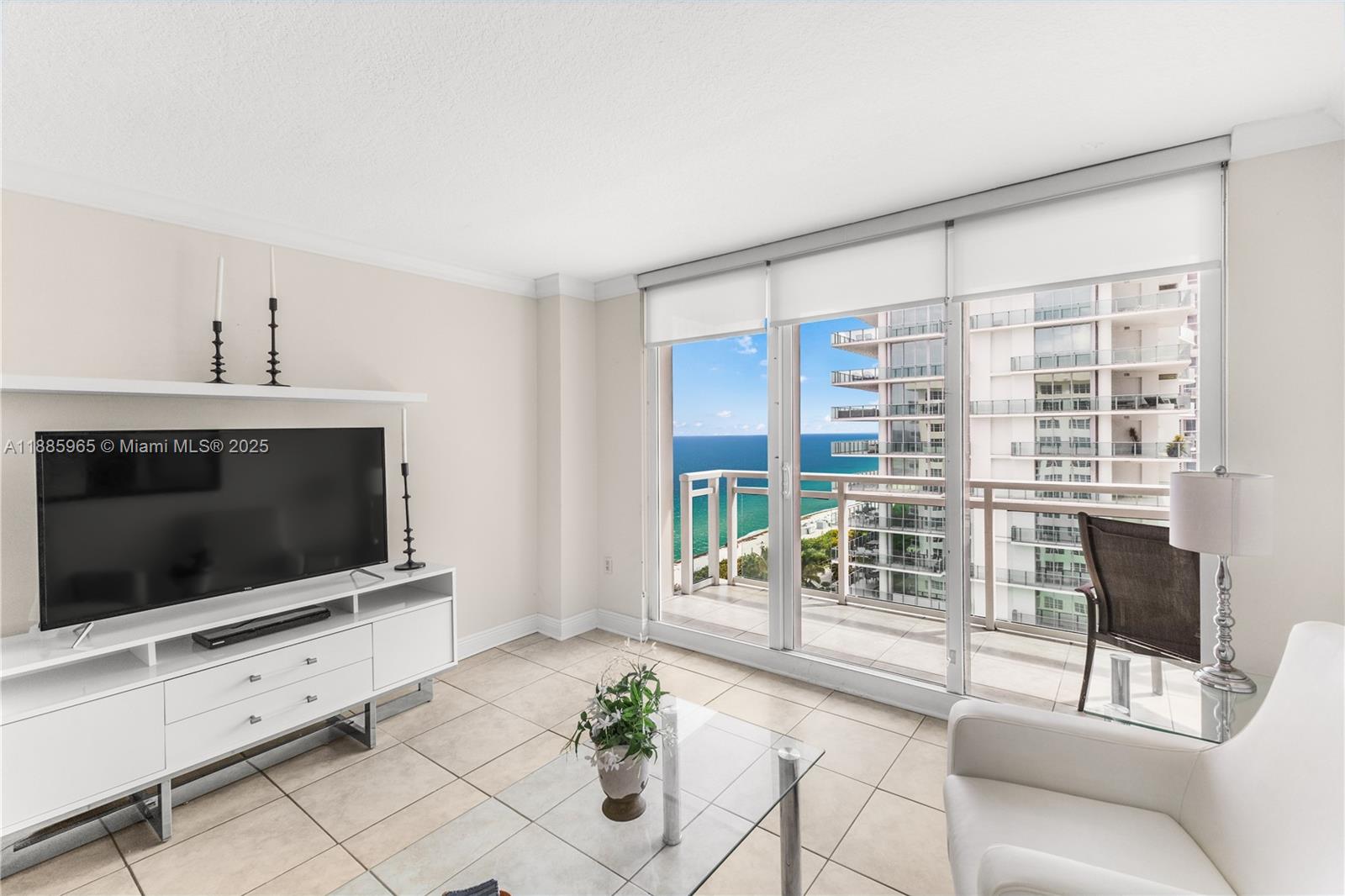 6917 Collins Avenue, Unit 1505 Miami Beach, FL 33141 - Photo 8 of 53 a living room with furniture a flat screen tv and a floor to ceiling window