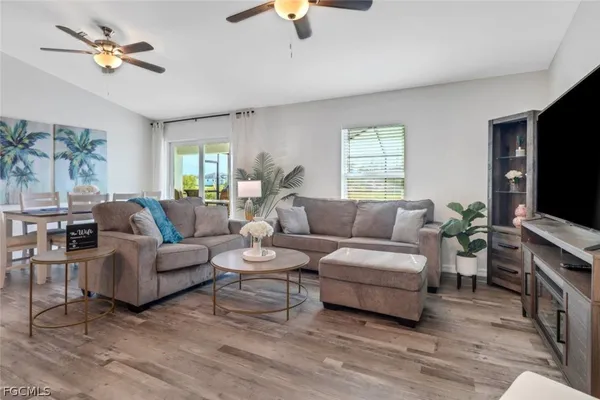 a living room with furniture a ceiling fan a lamp and a window