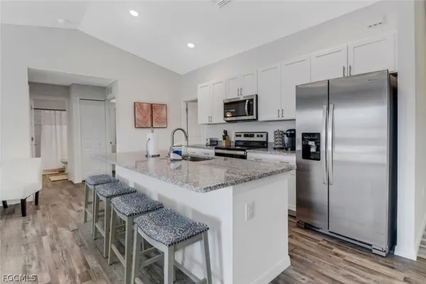 a kitchen with stainless steel appliances granite countertop a refrigerator a stove a sink a dining table and chairs