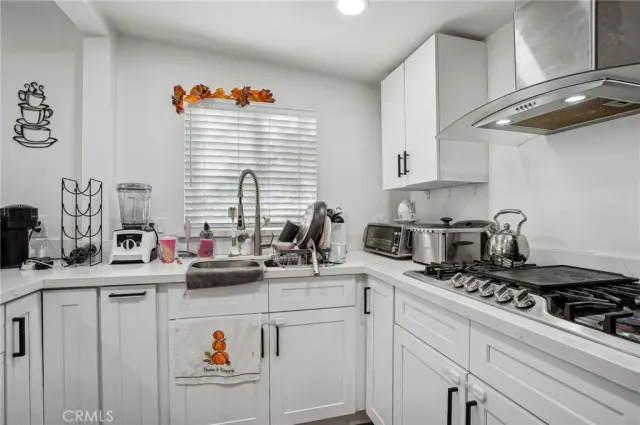 a kitchen with stainless steel appliances granite countertop a refrigerator a stove top oven a sink dishwasher and white cabinets with wooden floor