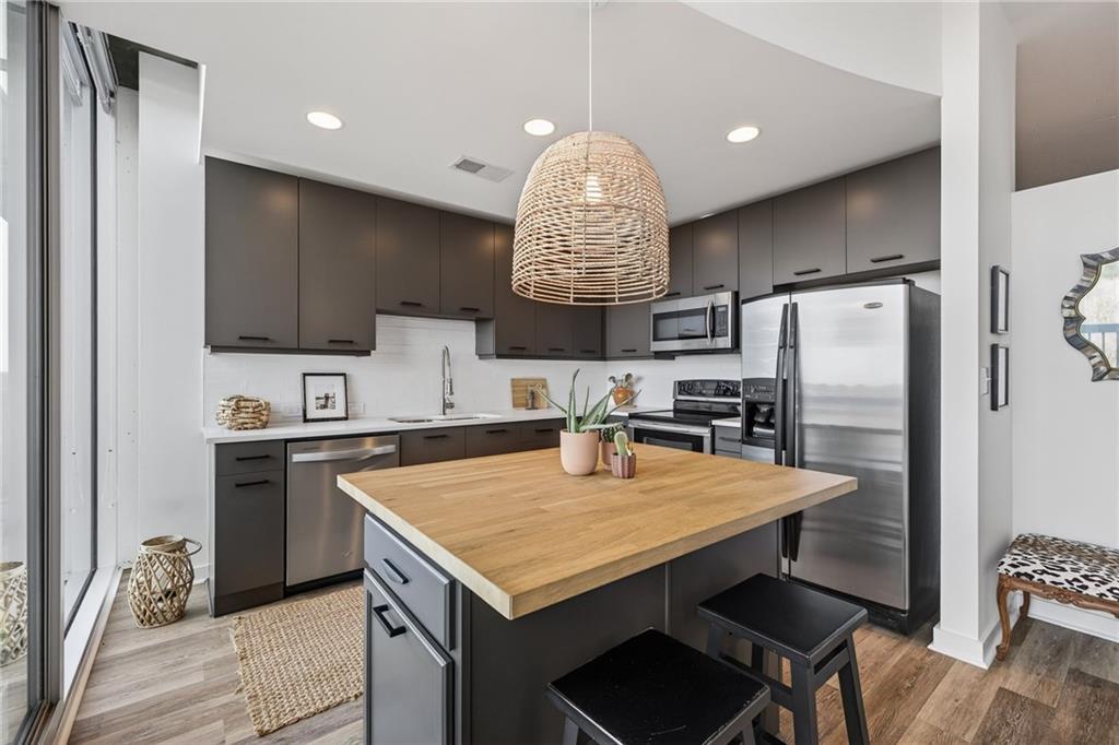 a kitchen with granite countertop a refrigerator a stove a sink dishwasher a oven with a dining table and chairs