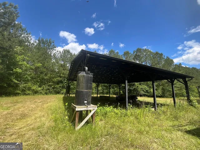 a backyard of a house with table and chairs a barbeque with wooden fence