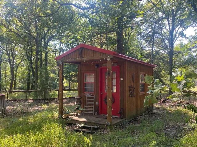 a view of a small house with yard and large trees