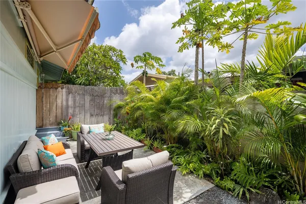 a backyard with table and chairs with potted plants