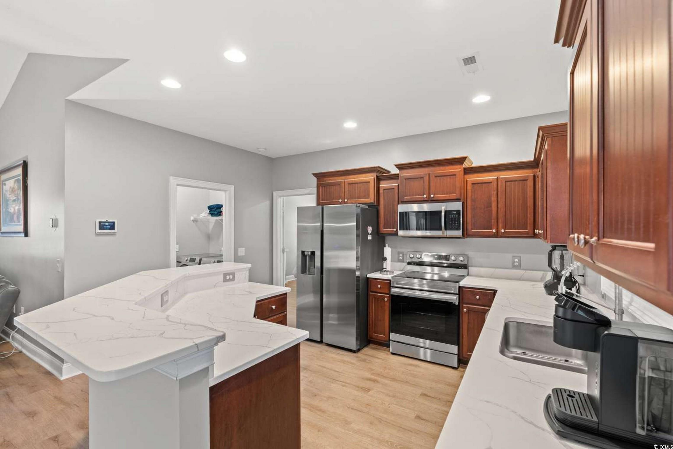286 Copperwood Loop Conway, SC 29526 - Photo 11 of 40 Kitchen featuring appliances with stainless steel finishes, a center island with sink, light stone countertops, recessed lighting, and light wood finished floors