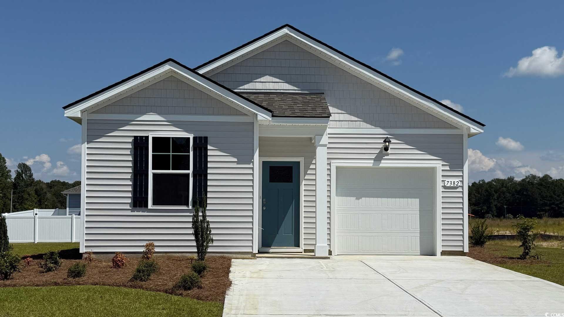 View of front of home with a garage, concrete driveway, and roof with shingles