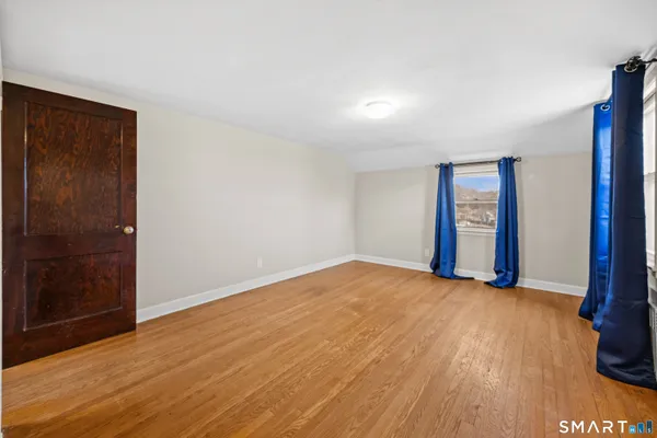 a view of an empty room with window and wooden floor