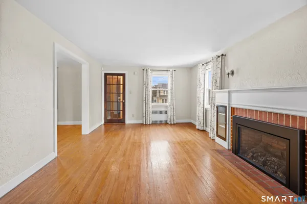an empty room with wooden floor fireplace and windows