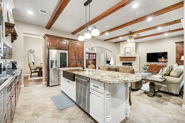 a kitchen with stainless steel appliances kitchen island granite countertop a table chairs sink and cabinets