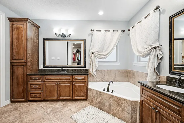 a bathroom with a tub a sink and a mirror