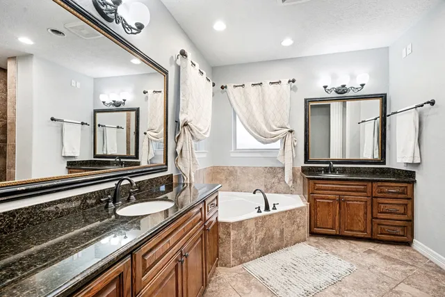 a spacious bathroom with a granite countertop tub sink and mirror