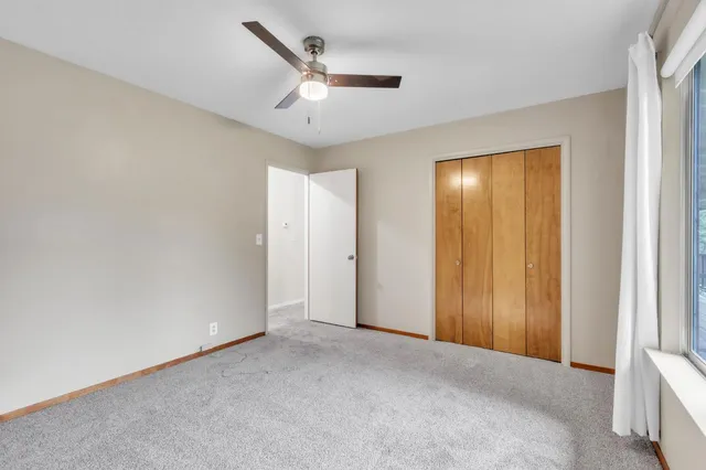 an empty room with windows and fan