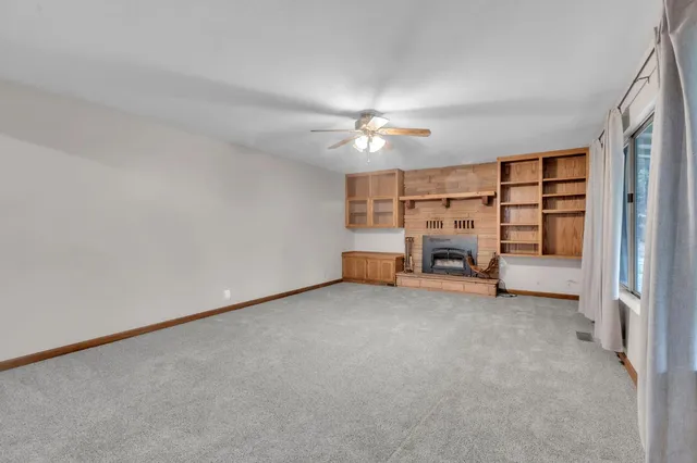 an empty room with chandelier fan and windows