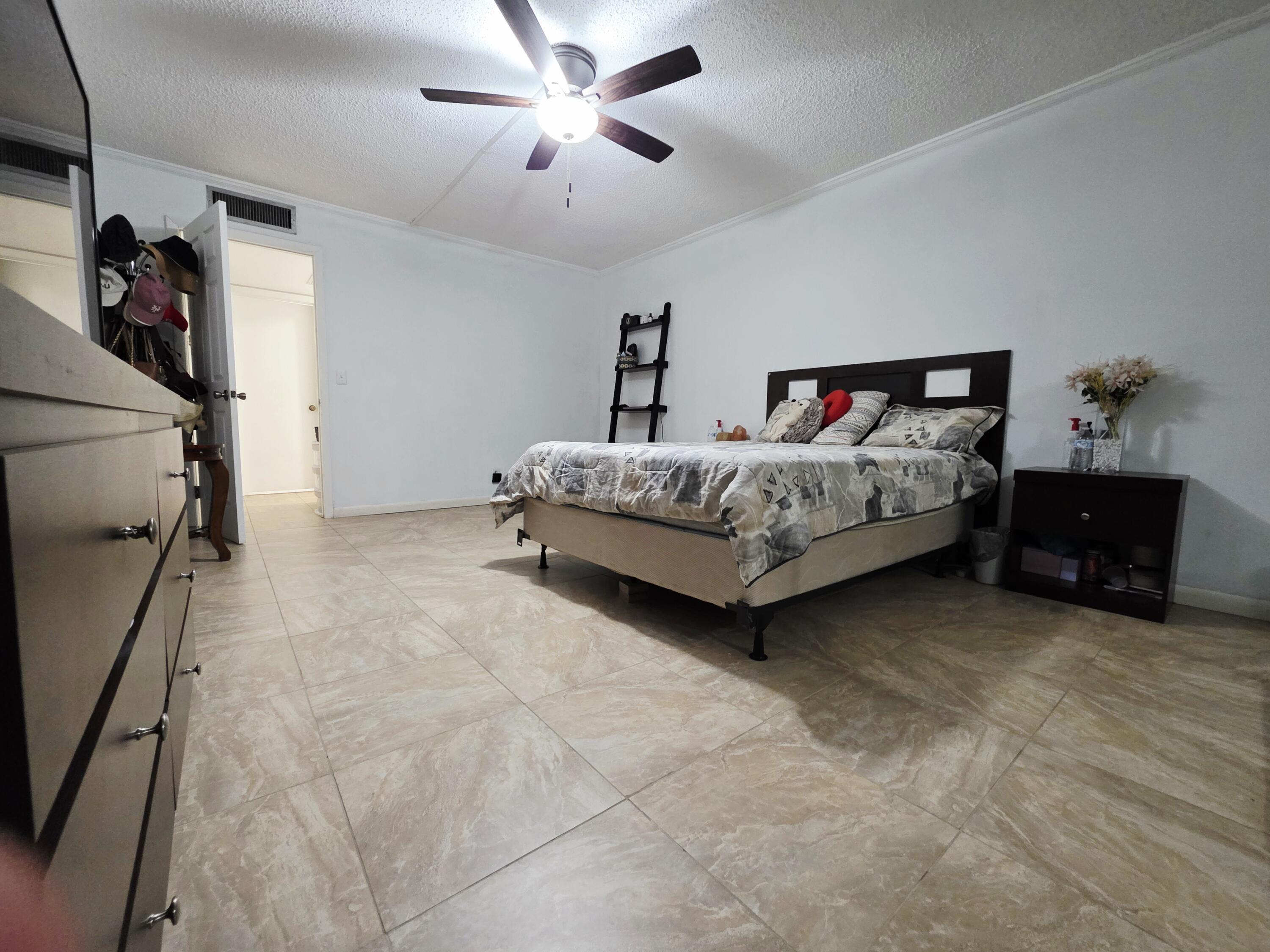 218 Woodland Road Palm Springs, FL 33461 - Photo 27 of 45 a spacious bedroom with a bed and a chandelier
