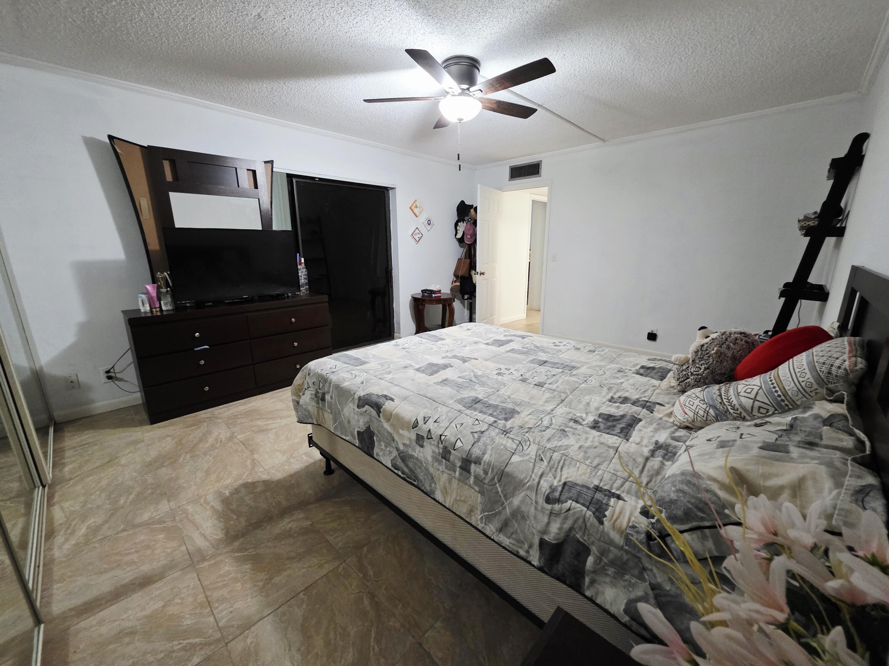 218 Woodland Road Palm Springs, FL 33461 - Photo 28 of 45 a bedroom with a bed and a flat tv screen on dresser