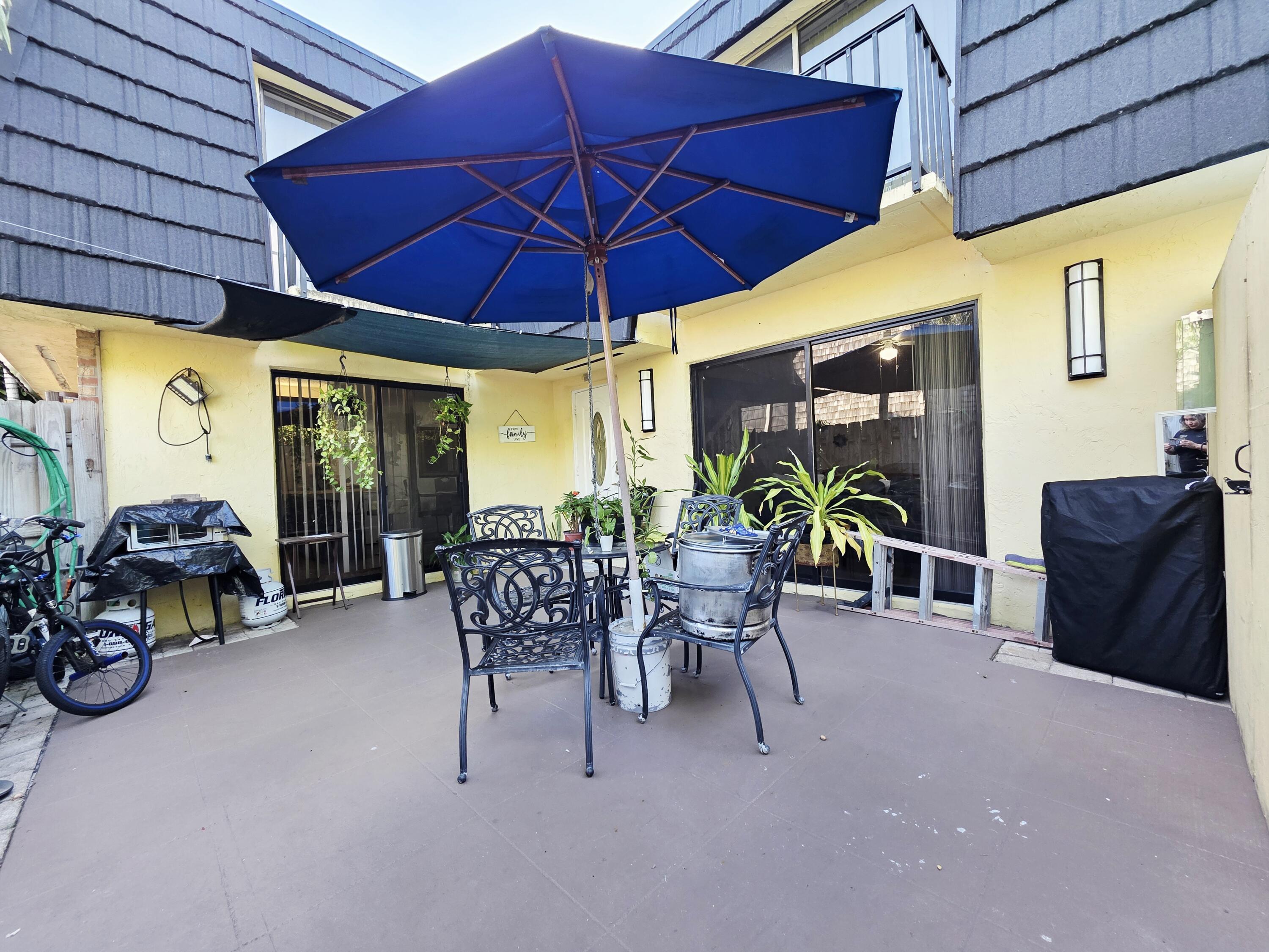 218 Woodland Road Palm Springs, FL 33461 - Photo 39 of 45 a view of a patio with table and chairs under an umbrella