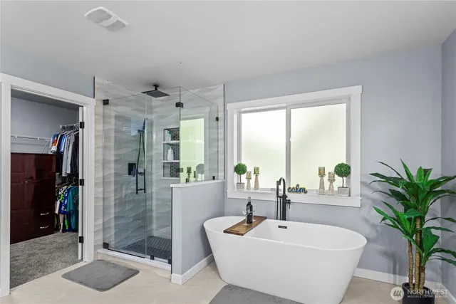 a spacious bathroom with a bathtub and potted plant