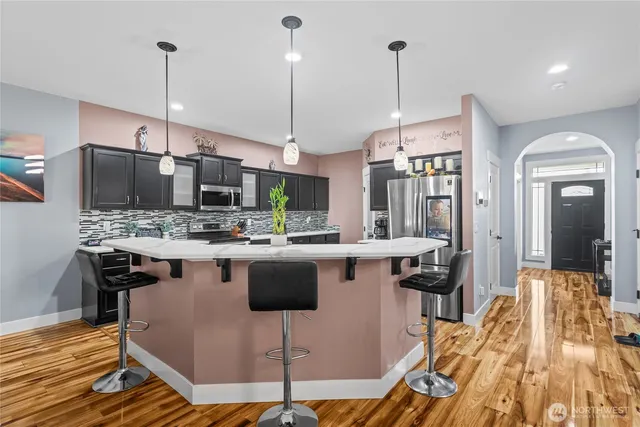 a kitchen island with stainless steel appliances kitchen island granite countertop a sink a counter space and wooden floor