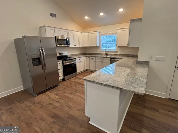 a kitchen with stainless steel appliances granite countertop a refrigerator a stove and a sink