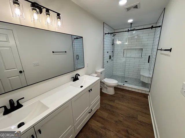 a bathroom with a sink a toilet and shower