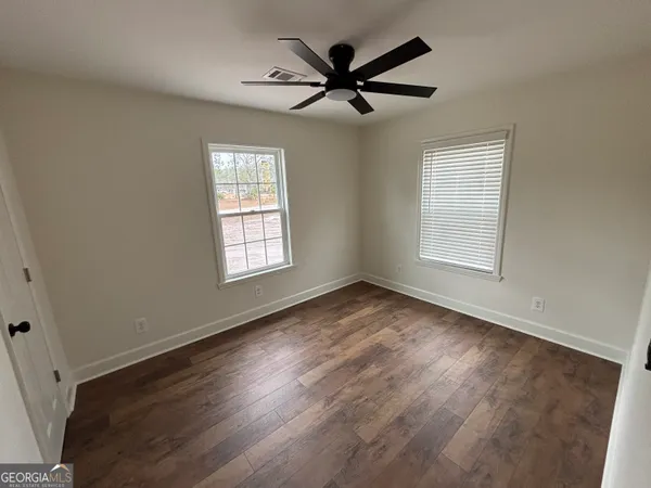 a view of empty room with wooden floor and fan