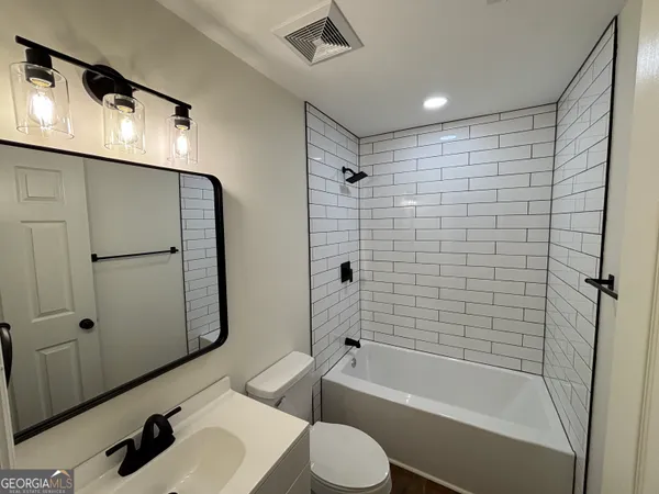 a bathroom with a bathtub shower sink vanity and toilet