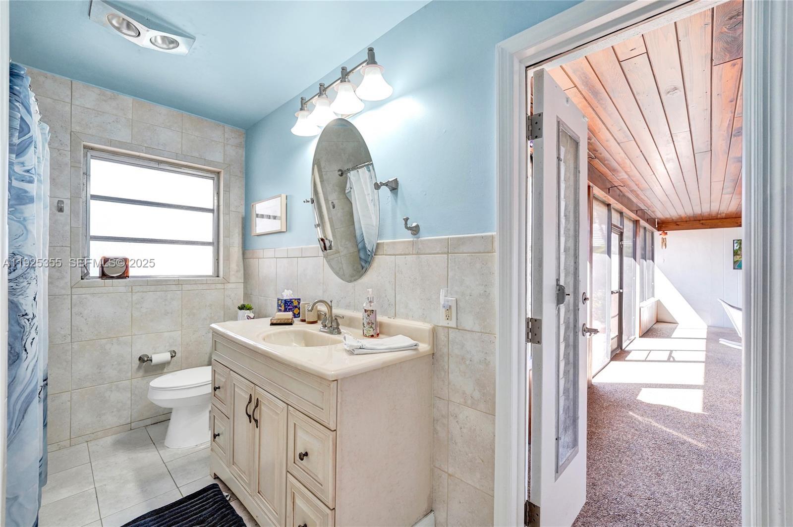 4060 Northeast 26th Avenue Lighthouse Point, FL 33064 - Photo 23 of 34 a bathroom with a double vanity sink toilet and a mirror